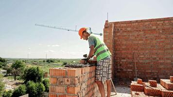 Bricklayer Builds Wall on Upper Floor Using Hollow Clay Bricks, Wearing Safety Gear Under Clear Sky video