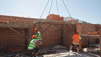 Brick Pallet Lifted Onto Platform as Construction Crew Works Inside Brick-Walled Structure in Heat video