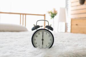 A clock is sitting on a bed in a bedroom photo