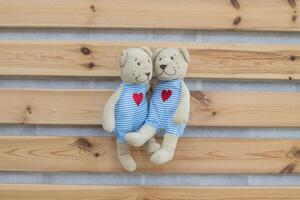 Two stuffed bears are sitting on a wooden wall photo