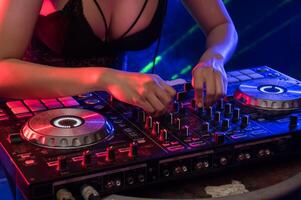 A woman in a black bra and panties is mixing music on a dj mixer photo