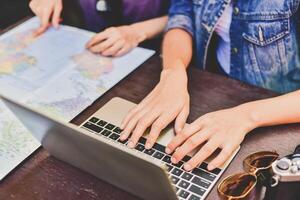 Two people are using a laptop computer and a map photo