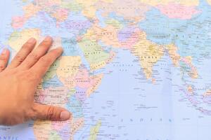 A hand is pointing at a map of the world photo