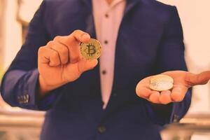 A man in a suit holding two bitcoin coins photo