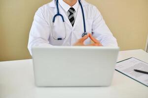 A doctor sitting at a desk with a laptop photo