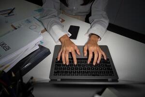 Late Night Typing. Close-up of hands typing on a laptop in an office. photo