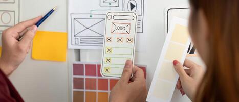 UX and UI Design. Hands holding design mockups and color palettes for mobile app. photo