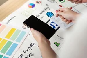 UX and UI Design. Hands holding smartphone and design elements for mobile application. photo