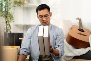 Gay man examining books while unpacking in a new home photo