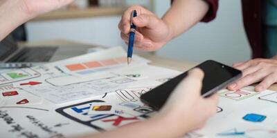 UX UI design collaboration. Team brainstorming with sketches and smartphone. photo