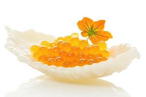 A white shell holds vibrant orange fish roe, garnished with a bright yellow flower. The scene emphasizes gourmet cuisine and elegant presentation. photo