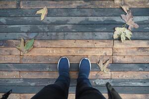Footsteps on a wooden walkway with autumn leaves photo