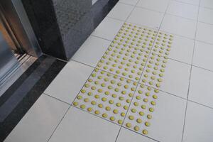 Yellow tactile ground indicators near elevator entrance photo