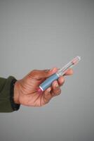 Hand holding a insulin against gray background photo