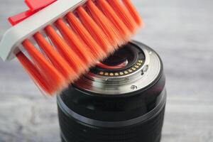 Camera lens cleaning with a brush on a wooden surface photo