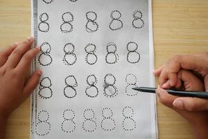 Child practicing number eight writing with dotted lines photo