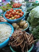 Fresh vegetables and fruits displayed at market stall, including tomatoes, potatoes, bean sprouts, ginger, and leafy greens, creating colorful and vibrant scene full of healthy produce photo