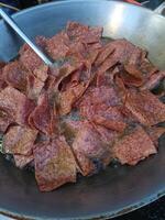 Crispy fried meat slices cooking in large pan, sizzling with oil, creating savory aroma and golden brown color, perfect for flavorful meal or snack photo