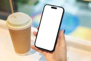 Woman Hand Holding Smartphone with Blank Screen and Coffee Cup. Ideal for app or website mockup. technology, lifestyle, coffee culture, or mobile app presentation. photo