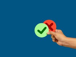 Hand holding two pieces of paper green and red with a checkmark and cross photo