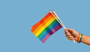 Close-up of rainbow flags showing in hand against a blue background photo