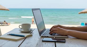 hand with laptop, digital nomad working at a beach cafe. photo