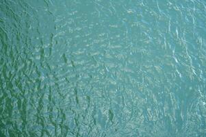 Top view of water surface texture with soft natural ripples. Background for eco-friendly design, peaceful concepts, and water sustainability. Aerial view blue green lake surface water background. photo