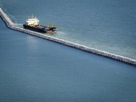 Marine construction vessel working on stone breakwater project in ocean. Coastal infrastructure development and harbor protection engineering work in progress. Port construction and coastal defense. photo