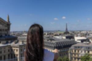 Girl looks at Paris from a viewing platform. Cityscape France, Paris. Blurred background. Copy space photo