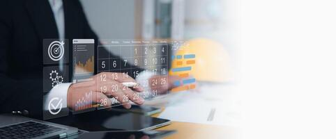 Businessman using futuristic digital calendar and data analytics dashboard on tablet, symbolizing business planning, project management, productivity, strategy, technology, and digital transformation. photo