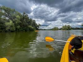 Kayaking on a lake with dramatic cloudy sky and lush green trees photo