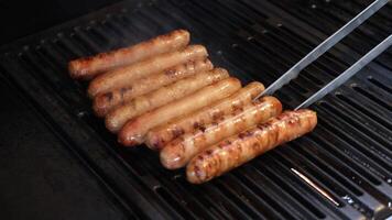 Sausages being grilled and turned with tongs video