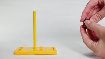 Hands manipulate magnets on a yellow stand, illustrating magnetic attraction and repulsion in a well-lit, static environment video