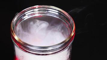 A beaker with dry ice creates swirling vapor, showcasing a mesmerizing chemical reaction under controlled lighting video
