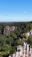 Aerial footage of Nimbin Rocks showcasing lush greenery and rugged cliffs under clear blue skies video