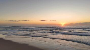 Serene sunrise over ocean waves with a person video