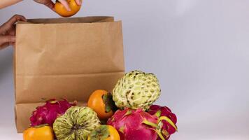 Hands placing fruits into a paper bag video
