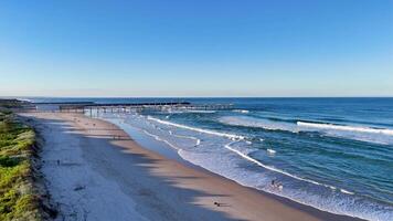 Drone captures serene Gold Coast beach with gentle waves and clear skies, highlighting the natural beauty and tranquility of the shoreline video