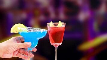 Blue and red cocktails clink together in a lively, colorful bar environment with dynamic lighting and vibrant hues video
