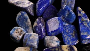 Lapis lazuli stones rotate smoothly against a dark backdrop, highlighting their vibrant blue hues and natural patterns video