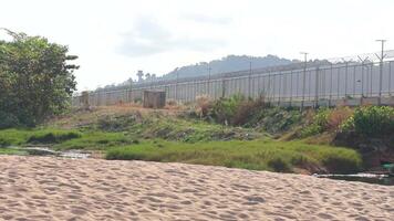 A tranquil beach scene in Phuket, Thailand, with lush greenery, distant hills, and soft natural lighting video