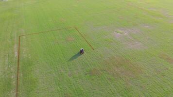A robot autonomously paints precise lines on a soccer field, showcasing advanced automation technology in a sunny outdoor setting video