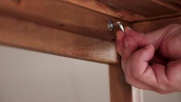 Hands tighten screws on wooden furniture using an Allen key. Close-up shots highlight precision and craftsmanship video