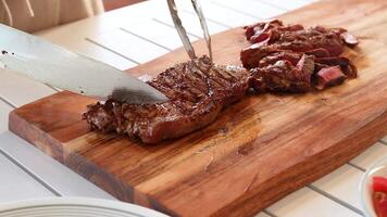 A steak is expertly sliced on a wooden board in a well-lit kitchen, highlighting texture and precision video