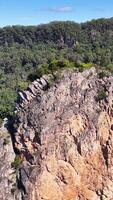 Drone footage captures the rugged beauty of Nimbin Rocks, showcasing lush greenery and striking rock formations under clear skies video