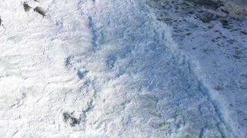 Drone footage captures waves crashing against rocky coastline at Byron Bay, Australia. Bright daylight enhances the dynamic ocean scene video