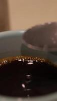 A spoonful of sugar is added to a steaming cup of coffee, creating a swirling effect in the liquid video