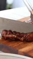 A chef slices a juicy beef steak on a wooden board in a well-lit kitchen setting video