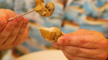 Hands extracting clams from shells with a tool video