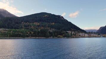 A tranquil scene of a lake with a mountainous backdrop in Queenstown, New Zealand, captured under soft daylight video